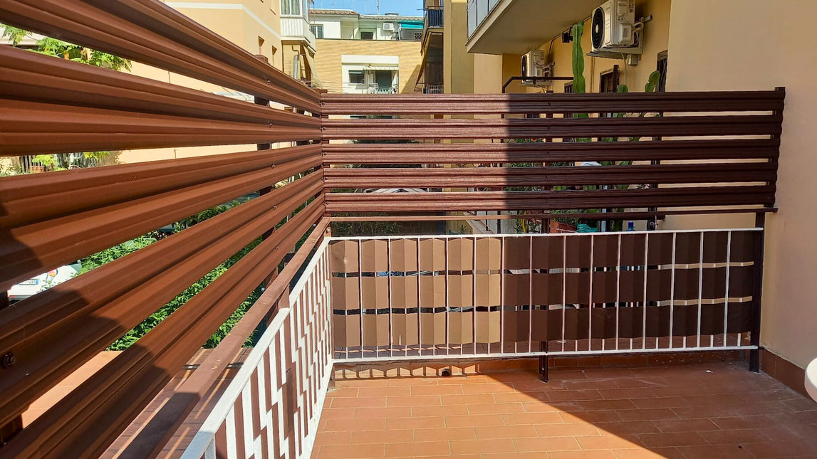 Dettaglio installazione su balcone doghe orizzontali frangivista giardino in acciaio zincato effetto marrone cioccolato, bordo e fissaggi visibili