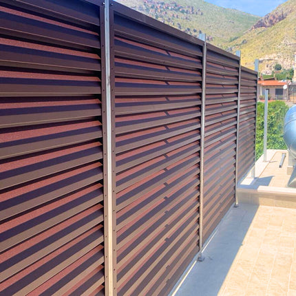 dettaglio installazione frangivista in acciaio zincato effetto cioccolato colore marrone su piloni esistenti per un ambiente industriale come copertura