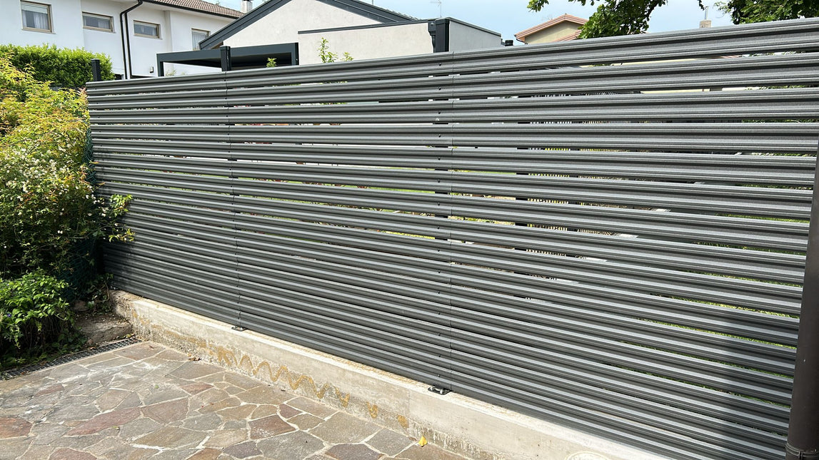 Installazione steccato orizzontale per giardino esterno con doghe in acciaio zincato colore grigio grafite, progetto completato con accessori inclusi