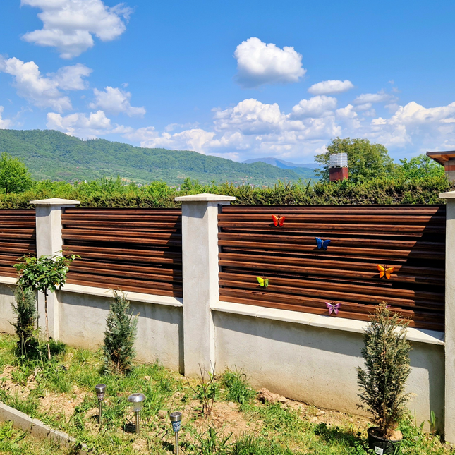 giardino delimitato con doghe orizzontali ancorate ai piloni del giardino effetto legno mogano